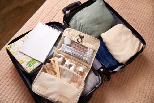 A suitcase open with a map, toothbrush, and various travel items neatly arranged inside.