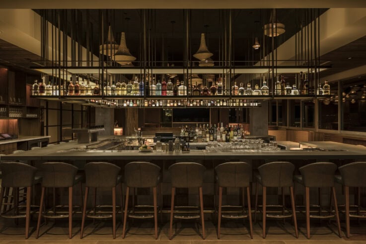 An ultra modern bar with bar stools and sophisticated midcentury modern inspired vibes at 4 Saints at the Kimpton Rowan Palm Springs Hotel