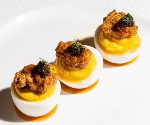 3 deviled eggs are arranged on a white plate.