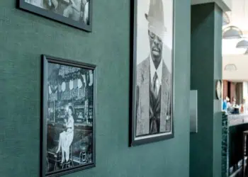 Photos of Black people hang on a green wall at Sly Rooftop in Washington, DC