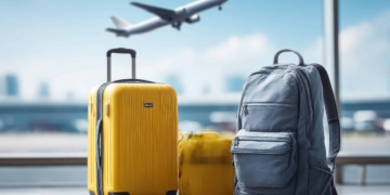 3 pieces of luggage at the airport as an airplane takes off behind them.
