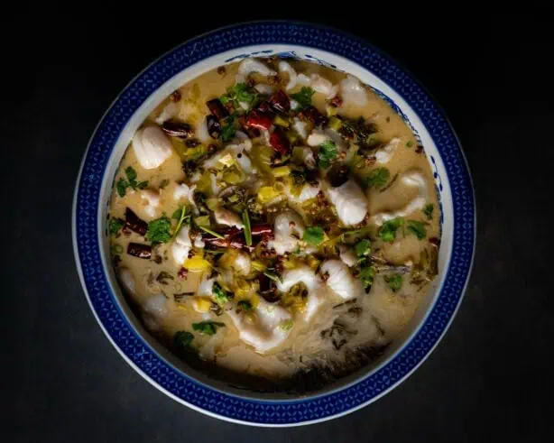 The sour cabbage hot pot sits on a dark table at The Fish Man Restaurant.