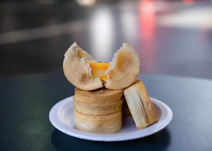 Wheel cakes from Peanuts Bubble Tea sit on a white saucer and dark table.