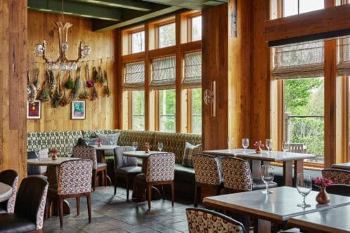 The dining room at the lodge features rustic decor, large windows, and a cozy atmosphere with wooden tables and chairs.